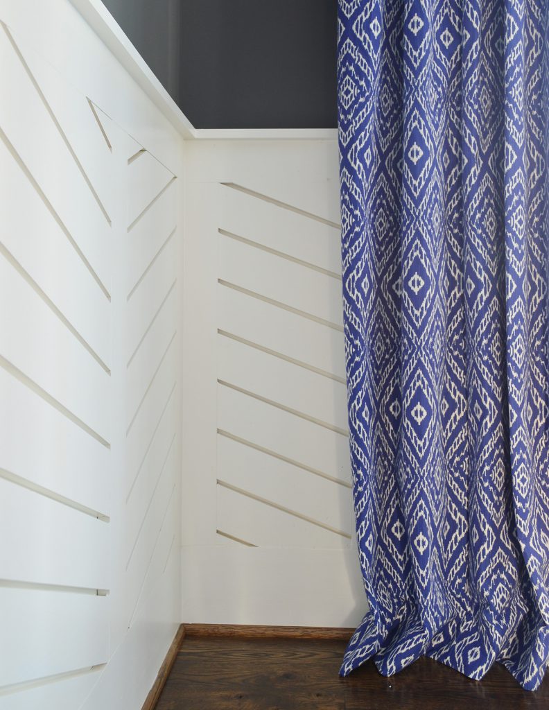 Chevron wainscotting with blue diamond curtain hanging to graze floor