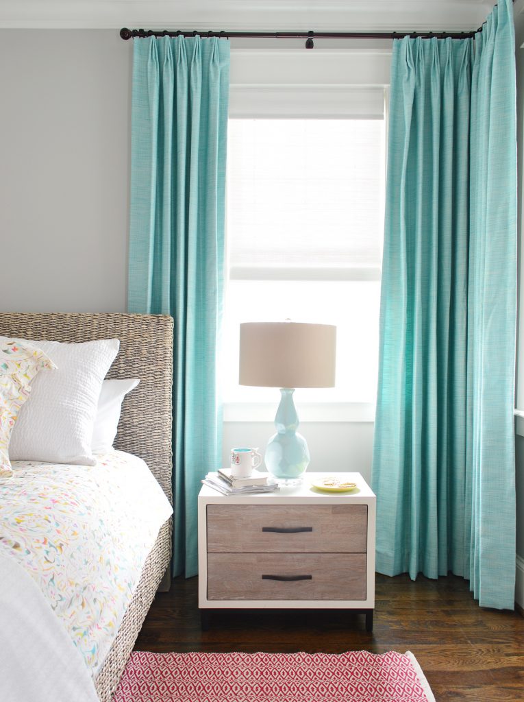 Blue aqua curtains hanging in bedroom behind nightstand